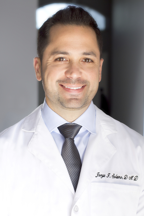 Dr. Jorge Solano wearing his dental white coat